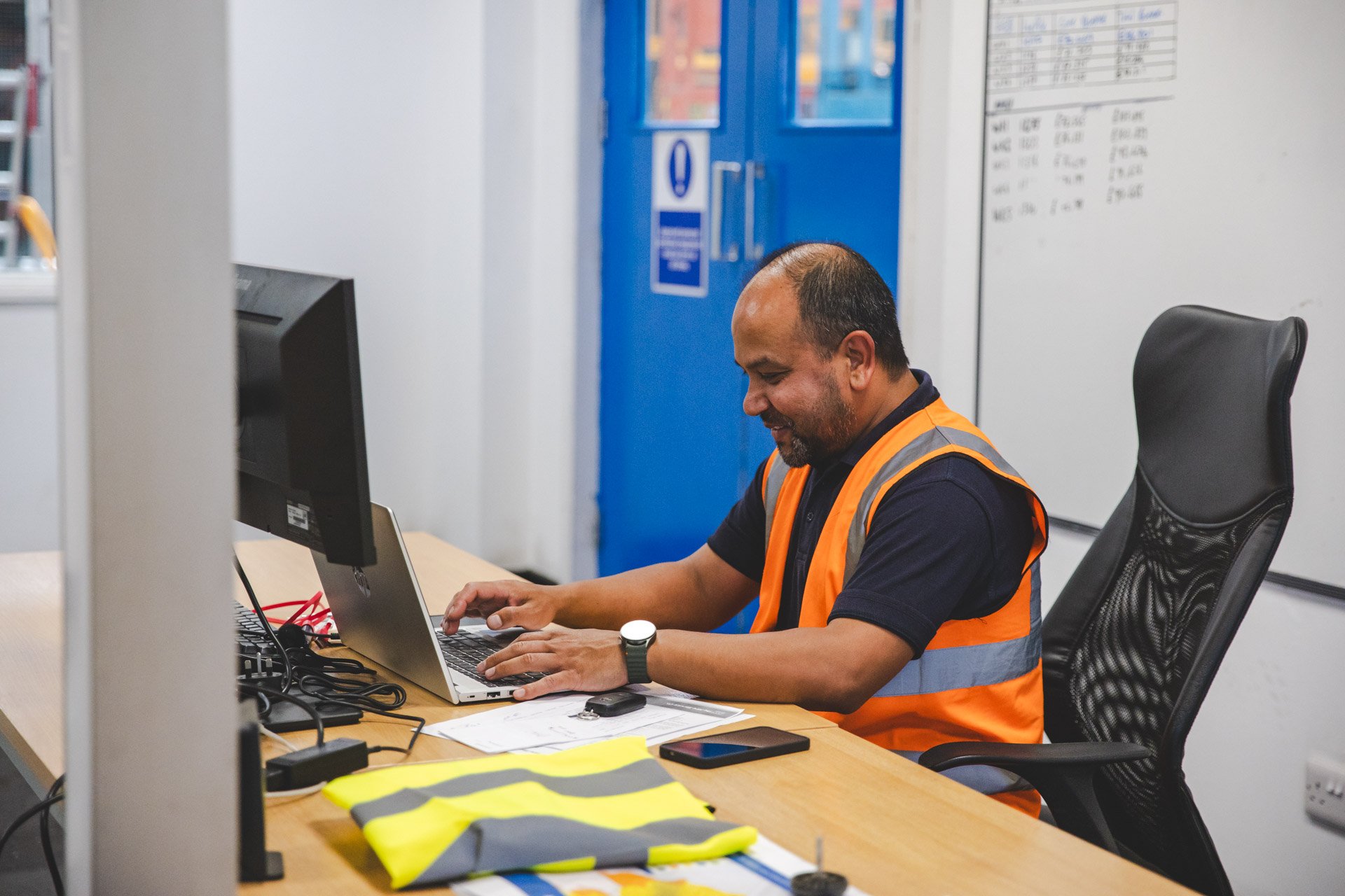 A worker, looking at his computer to compare the price of different equipment hire, to avoid overpaying.
