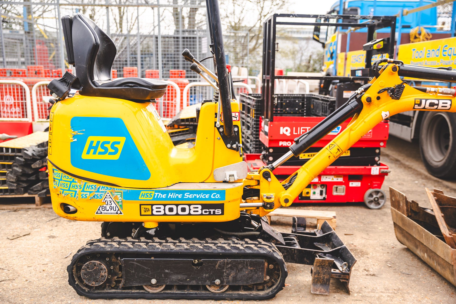 An mini excavator sits within a hire yard, representing the equipment and services that have shaped the HSS Hire brand over the years.