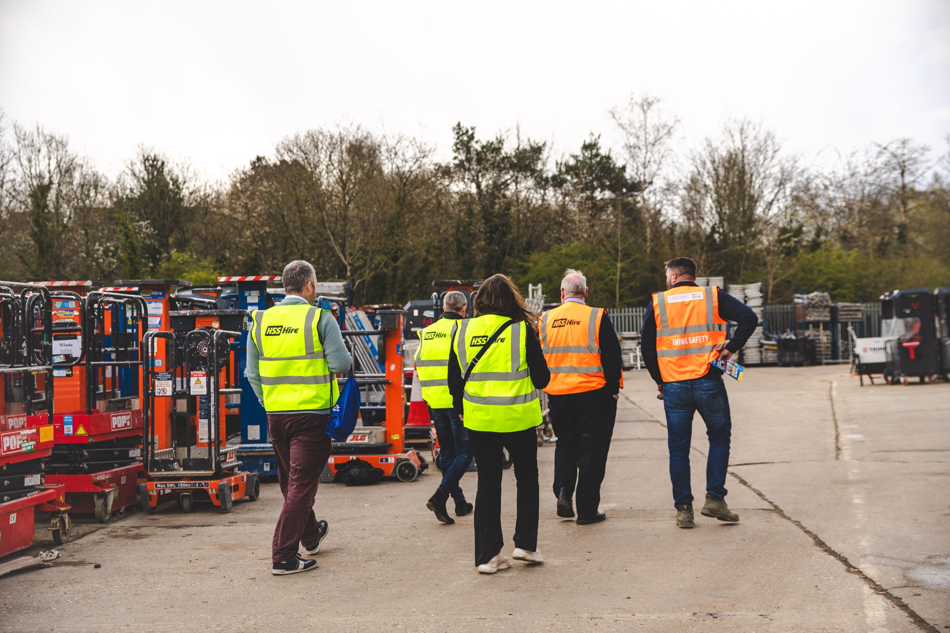 Visitors walk through an HSS: the Hire Service Company depot surrounded by hire equipment, illustrating the scale and evolution of the business behind the HSS Hire name.